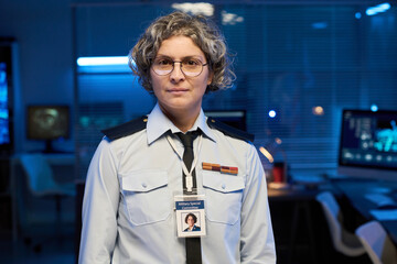 Aufkleber - Serious mature grey haired woman in eyeglasses and uniform looking at camera while standing in military command center