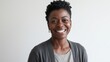 © Goodman - Smiling Mature Woman with Short Hair Radiating Positivity in a Professional Setting Wearing a Gray Cardigan and Necklace White Background