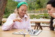 © ADDICTIVE STOCK - Outdoor chess game depicting multi-generational bond and strategy