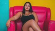© Duskcraft - Confident woman in black outfit sitting on vibrant pink chair against colorful wall