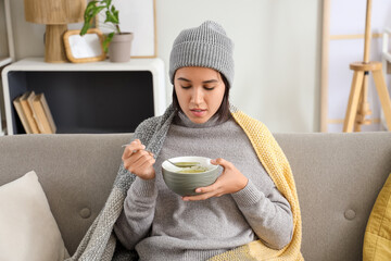 Wall Mural - Sick young woman eating chicken soup  at home