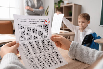 Wall Mural - Schoolgirl with results of test at desk in classroom, closeup