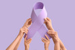 © Pixel-Shot - Hands holding paper awareness ribbon on lilac background