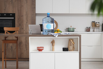 Wall Mural - Bottle of clean water with laptop on table in kitchen interior