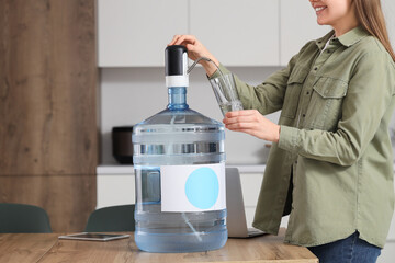 Wall Mural - Woman pouring clean water into glass in kitchen