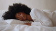 © Aris - Afro woman sleeping comfortably on white bed in luxury hotel