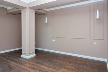 A large empty room with a wooden floor and a white wall