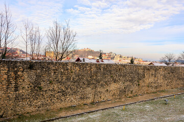 Wall Mural - A brick wall with a stone border and a snowy landscape in the background