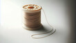 © Warittha - Denim An angled view of a spool of beige thread with a loose end hanging down The plastic spool is partial1