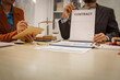 © R Photography - Two male and female lawyers sit at a table in an office, discussing legal matters related to opening a company.They focus on laws, regulations,and collaboration between in-house and business lawyers