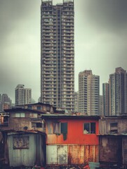 Aufkleber - Luxury skyscraper stands in stark contrast to nearby rundown shacks in an urban setting. Generative AI