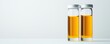 © Jeannaa - drug assessment development concept. Two glass vials containing amber liquid on a light background.
