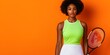 © nonni - Confident Female Tennis Player Posing with Racket Against Vibrant Orange Background in a Stylish Sport Outfit