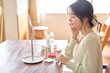 © lielos - 朝の身支度。自宅の部屋でスキンケアをしている若い女性。