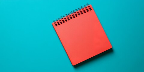 Leinwandbilder - A red notepad placed on a notebook page sits on a blue background, creating a contrasting visual of a red notepad against a blue backdrop.