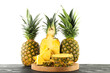 © New Africa - Whole and cut ripe pineapples on wooden table against white background