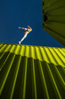 © VISTA by Westend61 - Young man jumping over green cargo containers under blue sky