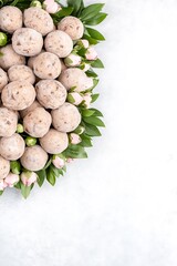 Wall Mural - Heart-shaped arrangement of sugared pastries and pink flowers on a white background.