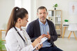 © Studio Romantic - Mature man patient talking to female doctor in white medical uniform in office during examination sitting in clinic. Medical worker listening to the patient's complaints. Healthcare concept.