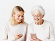 © Vasili - Two generations of women bonding while using smartphones, smiling and enjoying a shared digital experience in a bright setting.
