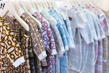 Poster - Rack of baby clothes with a variety of colors and patterns. The clothes are hanging on a white rack