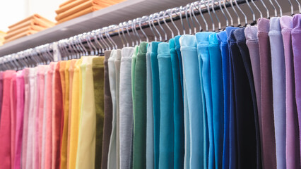 Poster - Rack of colorful pants hangs in a store. The pants are in a rainbow of colors, from pink to blue. The display is vibrant and eye-catching, inviting customers to try on the various styles