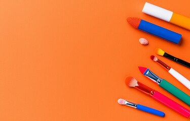 Cosmetic products for makeup displayed on a brown background.