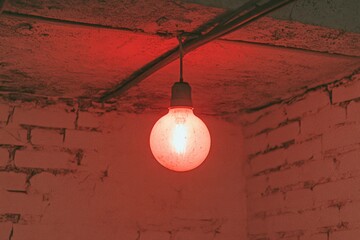 A dark depiction of a glowing lightbulb hanging in an abandoned room, with faint cobwebs and moody lighting creating a haunting atmosphere