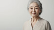 © bephoto - 白い背景で穏やかに微笑むシャツ姿の60代日本人女性