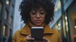 © O - African young woman texting on smartphone in urban setting with glasses and curly hair
