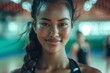 © S photographer - A confident young woman smiling, radiating positivity and determination in an energetic sports environment.