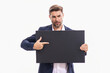 © Volodymyr - Man with blank banner isolated on studio background. Portrait of attractive man with empty blank poster. Man showing poster, pointing finger on signboard placard. Male presenting billboard or banner.