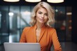 © Oleg - Smiling professional woman with short blonde hair working on a laptop in office environment.