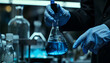 © Oleksiy - Scientist working with flask of light blue liquid on grey backgr