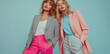 © The - Two stylish women model pastel pink and striped blazers with coordinating pants. One in hot pink, the other in light gray. A trendy fashion shoot.