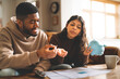 © Iryna - Couple discussing finances while planning budget with piggy bank in cozy living room during afternoon