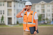© Volodymyr - Builder using phone. Portrait of builder in a construction site. Builder ready to build new house. Construction builder wear building uniform and helmet.