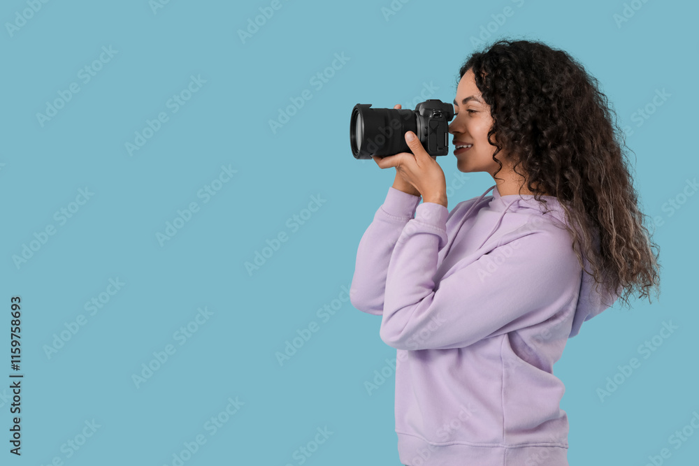 Female African-American photographer with camera on blue background
