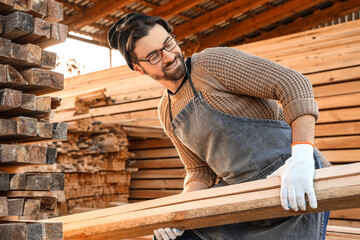 Wall Mural - Male carpenter stacking wooden planks at sawmill