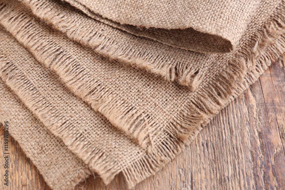 Pieces of burlap fabric on wooden background