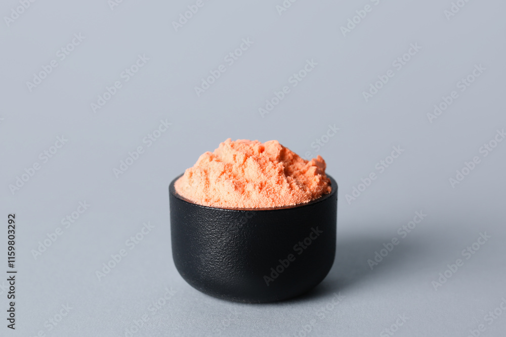 Bowl of orange powder pigment on light background