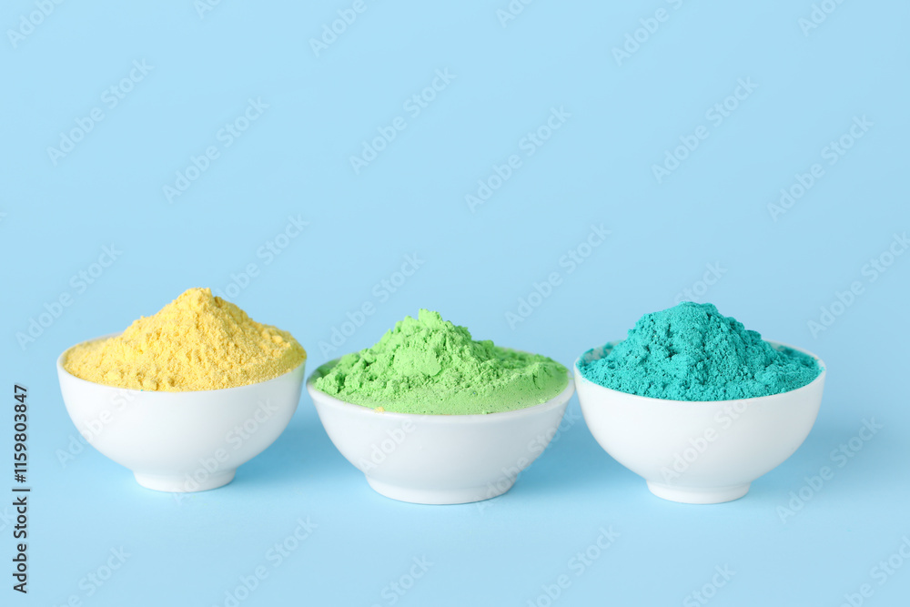 Bowls of powder pigments on blue background