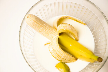 A peeled banana rests in a glass bowl of milk, its simplicity and soft tones evoke freshness and minimalism against a clean white background.












