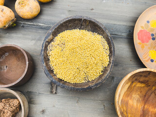 Wall Mural - A bowl of yellow grains sits on a wooden table next to other bowls