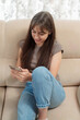 © timonko - Relaxed young woman chatting on the phone while lounging on a couch in her living room