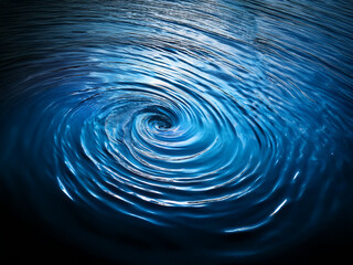 Leinwandbilder - A mesmerizing whirlpool of deep blue water, swirling into a central vortex.  The concentric circles ripple outwards, creating a hypnotic effect against a dark background.  Light reflects on the surfac