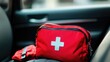 © Alla - A red first aid kit sits on the passenger seat of a car, ready to use in case of emergency