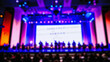 People at an award ceremony standing together on stage at a blurred event