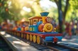 © Anton - Brightly colored toy train moves along sunny track, surrounded b