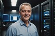 © ThomasLENNE - Close portrait of a smiling senior Bosnian male IT worker looking at the camera, against dark server room blurred background.